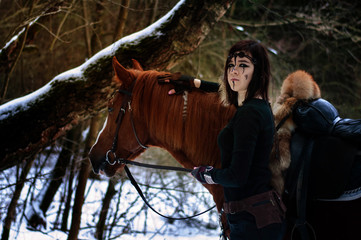 a Viking girl next to a red horse painted in black runes.