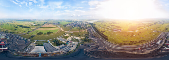 Aerial panoramic 360 degree banner view of a large plant with mines for the extraction of coal . Mounds of black coal near production and industry under blue sky with clouds.