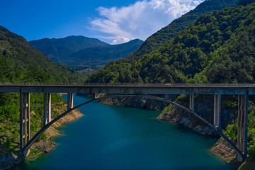 Fototapeta na wymiar Aerial view, automobile bridge, Lake Valvestino, Italy. Cumulus clouds in the blue sky