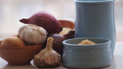 clay jugs, saucers with cereals, onions and garlic on the background of the window