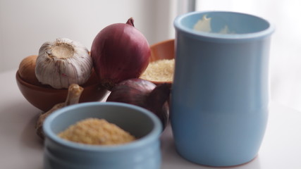 clay jugs, saucers with cereals, onions and garlic on the background of the window