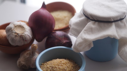 clay jugs, saucers with cereals, onions and garlic on the background of the window