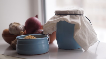 clay jugs, saucers with cereals, onions and garlic on the background of the window