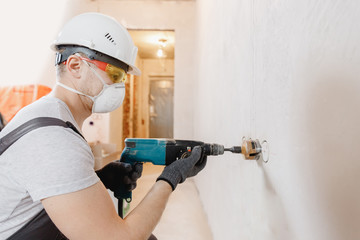 Builder worker pneumatic hammer drills hole in concrete brick wall with diamond crown for electric...