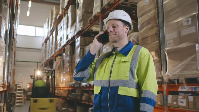 Worker in logistics warehouse on the phone receiving instructions