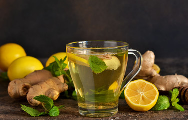 Hot tea with ginger, mint and lemon on a brown concrete background. Horizontal focus.