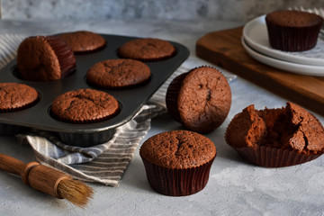 Chocolate muffins with chocolate moss sauce and mint on a concrete background.