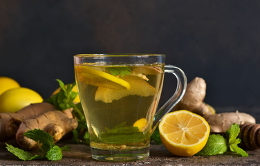 Hot tea with ginger, mint and lemon on a brown concrete background. Horizontal focus.