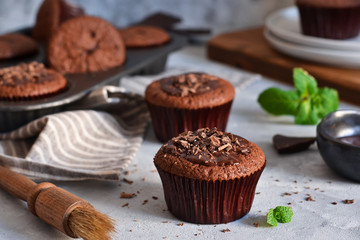 Chocolate muffins with chocolate moss sauce and mint on a concrete background.