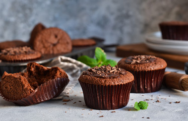 Chocolate muffins with chocolate moss sauce and mint on a concrete background.