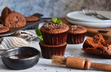 Chocolate muffins with chocolate moss sauce and mint on a concrete background.