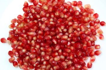 Heap of red pomegranate seeds on a white background