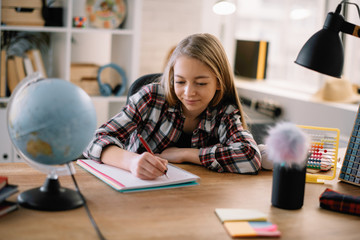 Beautiful girl learning at home. Schoolgirl doing homework.