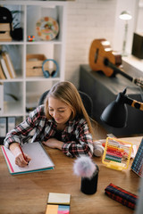 Beautiful girl learning at home. Schoolgirl doing homework.
