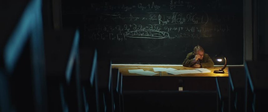 Professor or scientist is thinking about solving a complex equation or formula. Cant find the correct conclusion. Evening, night, overtime, empty University hall.