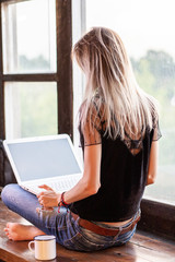The girl freelancer works with a laptop.   The woman with blond hair sitting on a wooden...