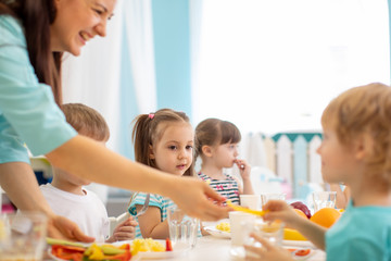 Obraz na płótnie Canvas Group of kindergarten kids have lunch in day care