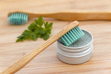 Bamboo toothbrushes and solid toothpaste in metal tin on wood background. Zero waste, plastic free, environment concept