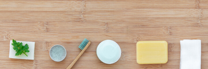 Zero waste bathroom web banner with copy space. Bamboo toothbrushes, solid toothpaste, solid shampoo and soap on wood background. Plastic free, environment concept. Top view, flat lay