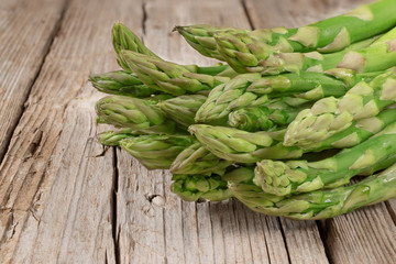 Bunch of fresh green asparagus spears on brown rustic wooden table, macro photo. Vegan concept