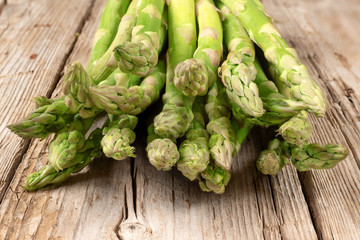 Bunch of fresh green asparagus spears on brown rustic wooden table, macro photo in perspective. Vegan concept