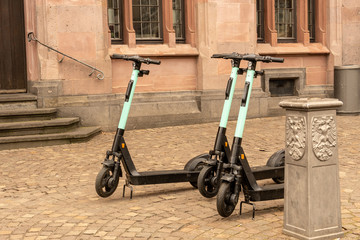 After use, three e-scooters are parked in front of a historic building in the middle of the city
