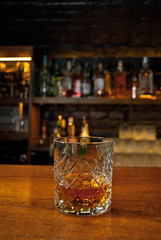 Yellow cocktail on bar counter. Whiskey, rum or brandy on the background of bottles with alcohol....