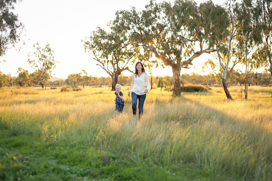 Mother and son playing together in a picturesque field with long grass at sunset. Family time. Mother-son bond. Beautiful image for mother's day with copy space.