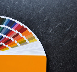 Color palette guide, fan, catalogue on  black background. Ral color fan  with orange cover on stone texture