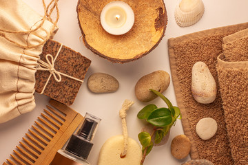 Spa and wellness concept, natural coffee scrub soap in cotton eco bag, coconut oil cosmetic, peeling sand stone,towel,wooden haircomb.Beige dayspa set.Pastel bathroom accessories and products top view