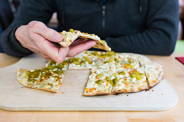 Man eating French German traditional dish tarte flambee Flammekueche on wooden cutting board