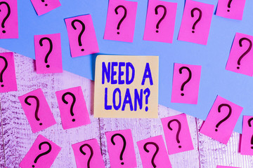 Conceptual hand writing showing Need A Loan Question. Concept meaning asking he need money expected paid back with interest Crumbling papers with thick cardboard on the wooden table