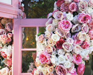 Decoration of multi-colored roses on a pink glazed cabinet door. Festive decor for a wedding or anniversary interior background