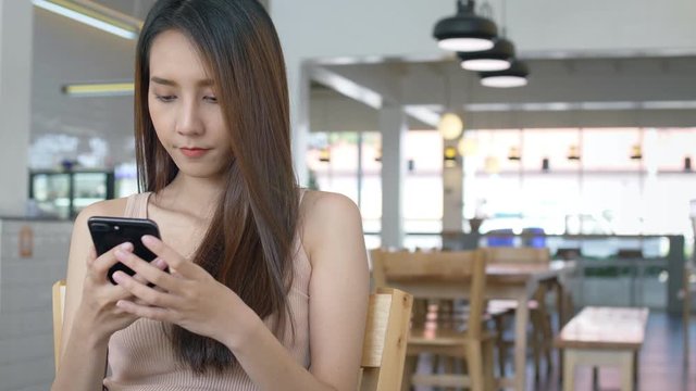 Young beautiful Asian woman working with mobile phone in coffee shop with copy space