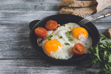 Fried egg. Close up view of the fried egg on a frying pan with cherry tomatoes and parsley