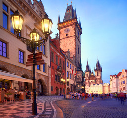 Prague, Old City Hall on the Town Square early evening, historic architecture of houses and church of St. Mary before Tyn illuminated with setting Sun and street lights. Beautiful Prague on sunset.