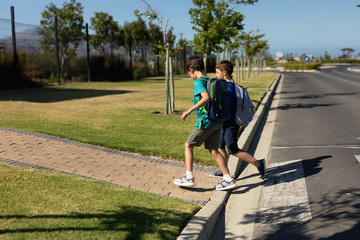 Two schoolboys reaching the pavement after crossing the road