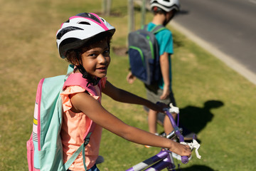 Fototapeta na wymiar Schoolgirl sitting on a bicycle and wearing an helmet