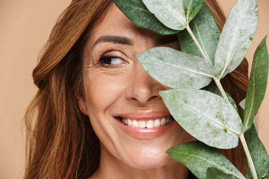 Portrait of joyful adult woman posing with eucalyptus and smiling
