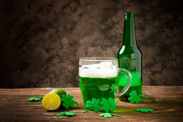 St. Patrick's Day, green shamrock with a full cold glass of traditional green beer and foam on a wooden background.