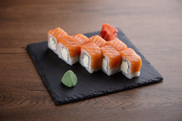 Appetizing sushi set on a stone plate on a dark wooden table