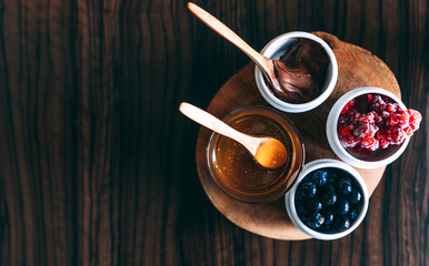 Fresh blueberries and frozenraspberries, honey and hazelnut paste. Served on the table. View from top. Space on the left.
