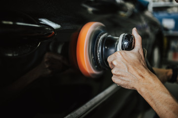 Car detailing - Hands with orbital polisher in auto repair shop. Selective focus. Old film color...