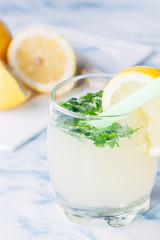 Glass of lemonade with aromatic herbs with the lemons cut