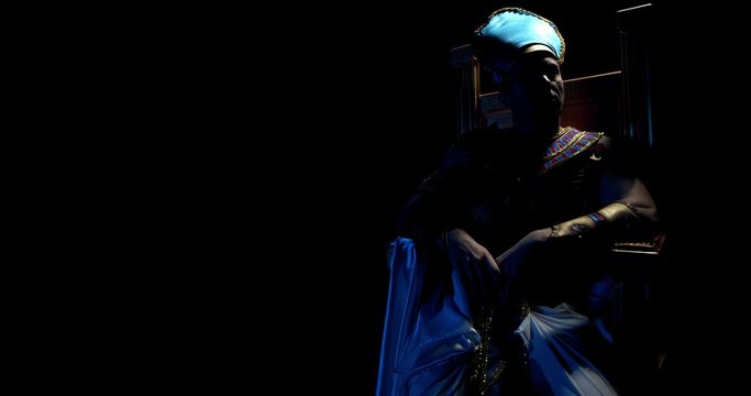 Dramatic lighting, ancient egyptian leader is sitting on a throne in the dark