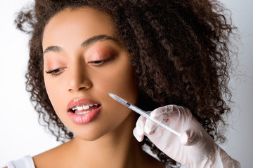 Fototapeta premium beautiful young african american woman making beauty injection, isolated on grey