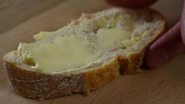 man spreads butter on bread with a knife