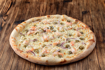 Italian seafood pizza with prawns and capers on rustic textured background
