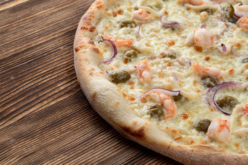 Italian seafood pizza with prawns and capers on rustic textured background