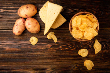 Crisps and cheese on dark wooden background.